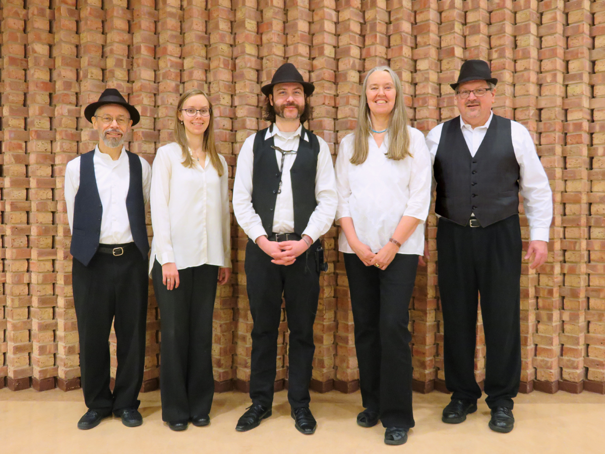 Photo of the Ensemble M’chaiya as a quintet standing against a brick wall.