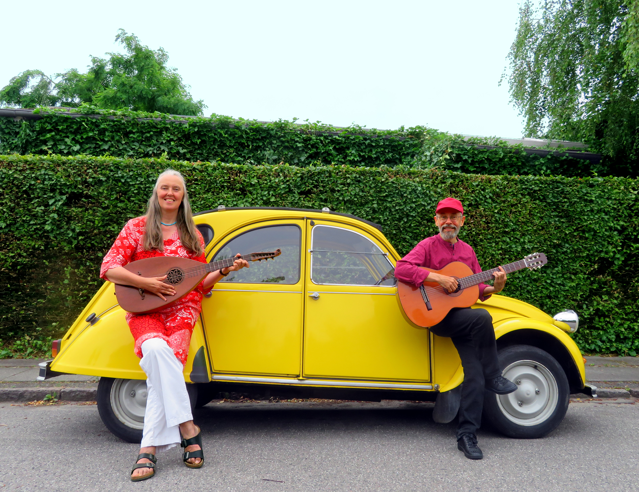 Photo of Jutta & the Hi-Dukes as a duet in front of a yellow Deux Cheveaux car