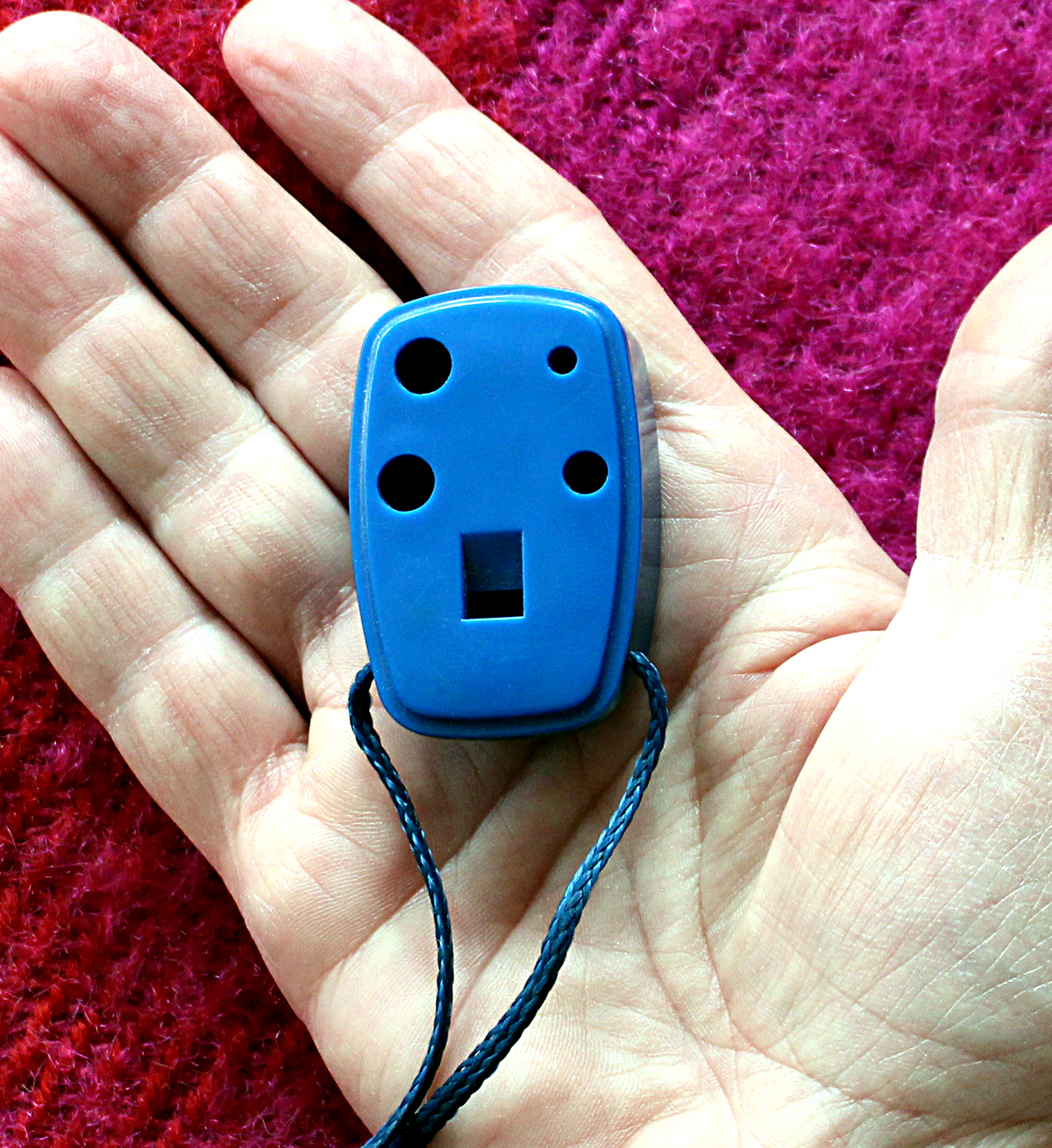 Blue ocarina laying in the palm of a hand.